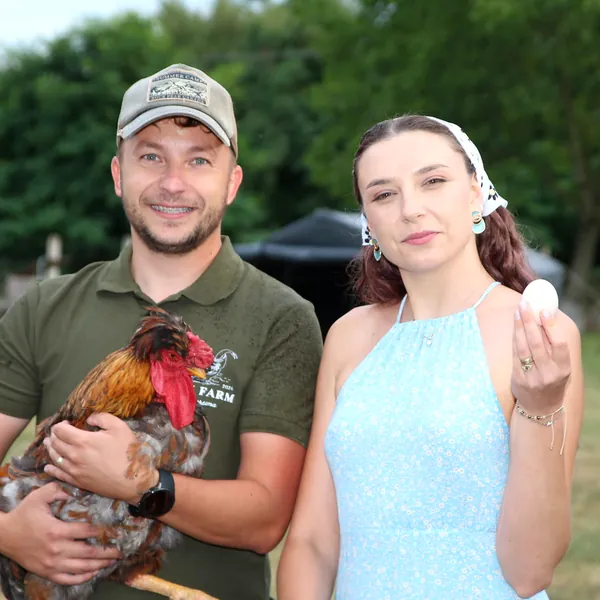 Márk egy kakast, Anna egy tojást tart a kezében a PIPU Farmon